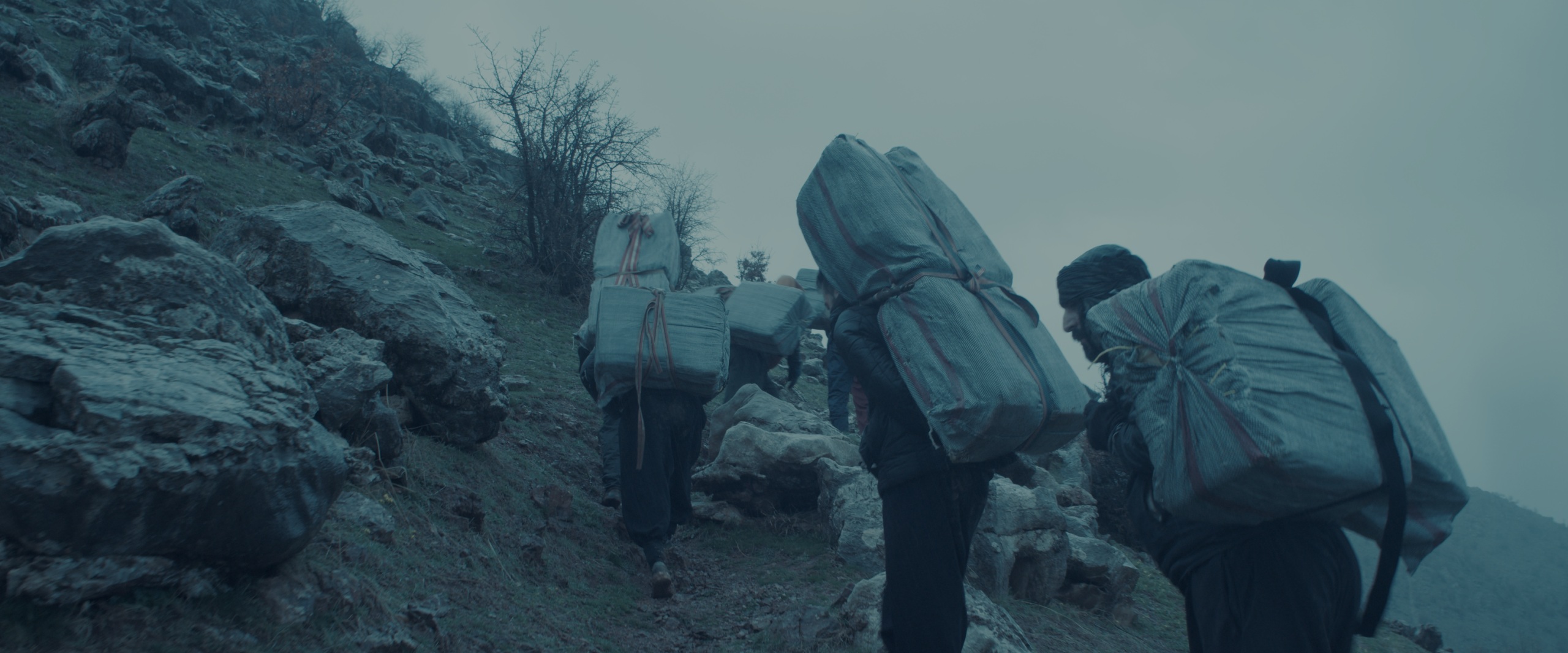 A group of men smuggling boxes up a mountain.